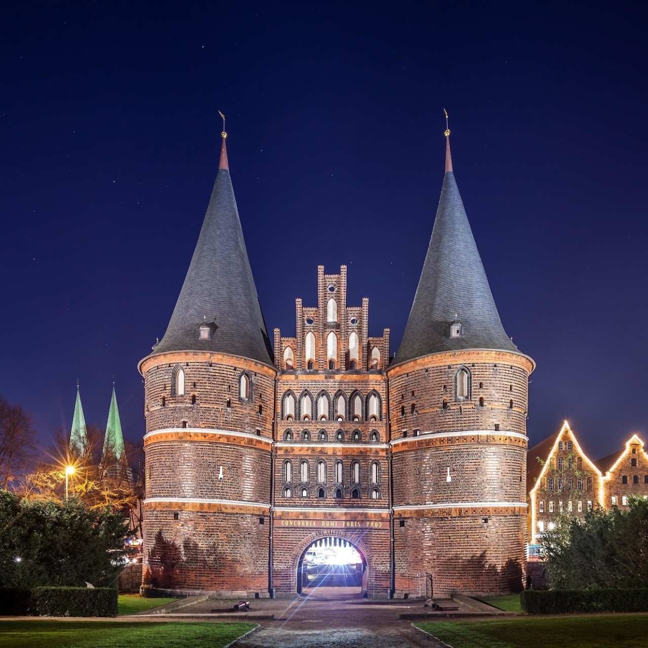 An imposing, two-towered gate in Lubeck, shown aglow at night