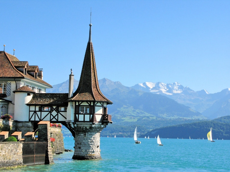 A scenic section of Lake Thun, with a pointed tower perched out over the water