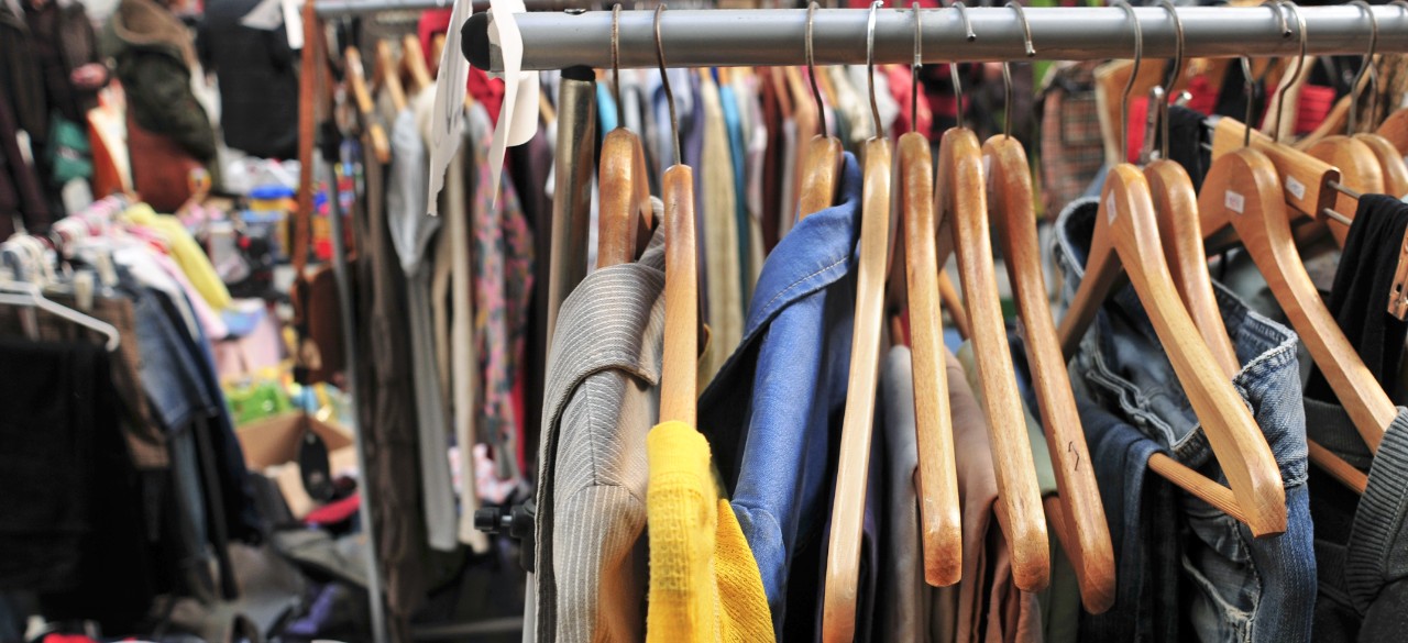 clothes hanging on a rack in a flea market