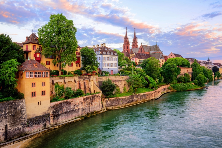 A waterside view of Basel's historic buildings at sunset